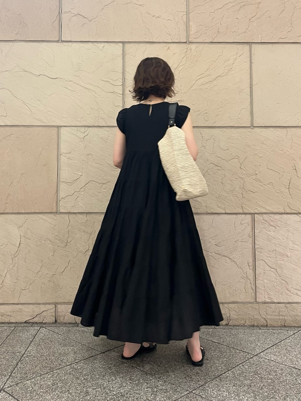 ベージュ系のかごバッグ、ブラック系のワンピース、ブラック系のサンダルを着用したレディースの夏コーディネートの3枚目の写真