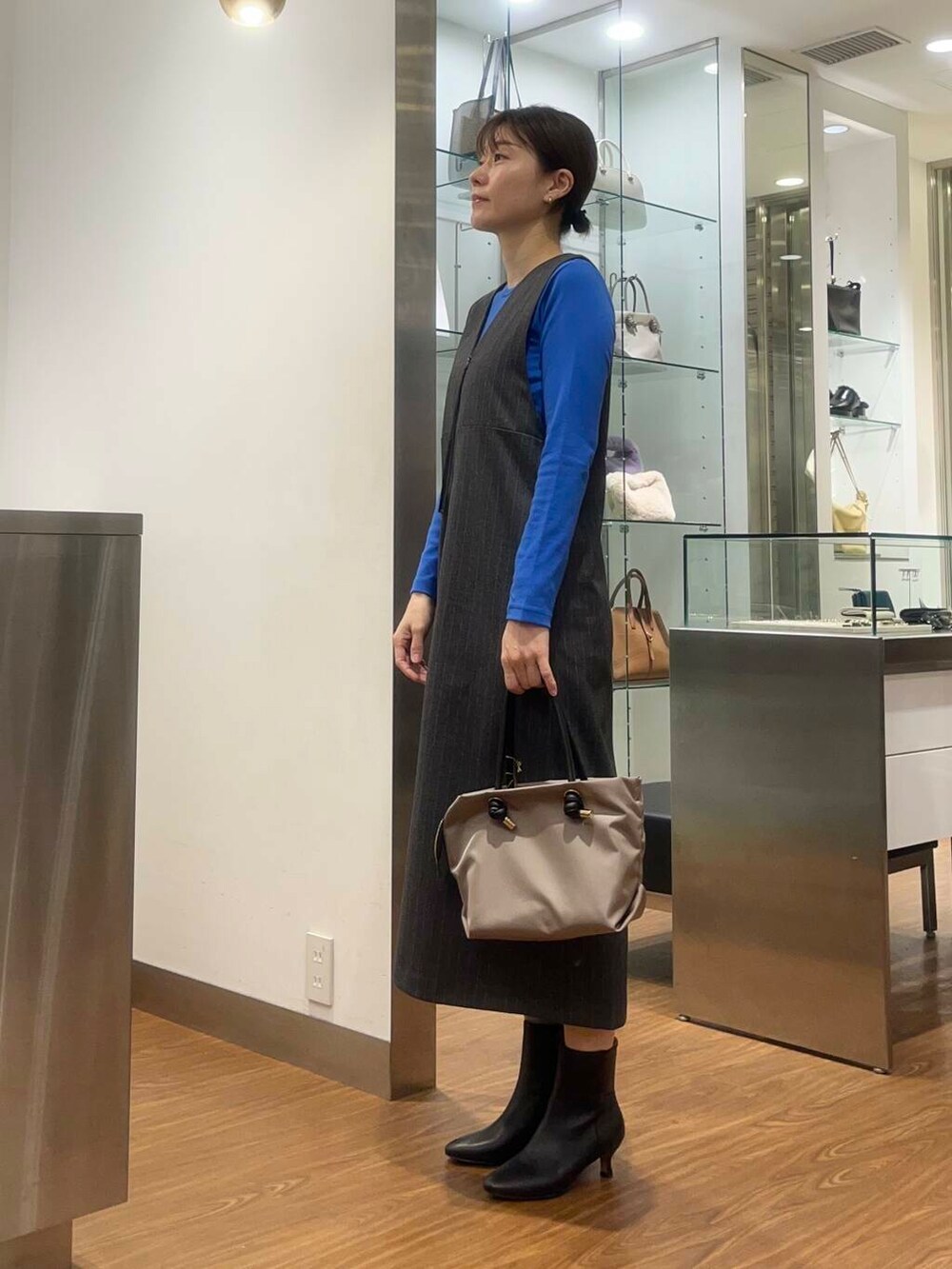 ブラウン系のハンドバッグ、ブルー系のTシャツ/カットソー、ブラック系のブーツを着用したレディースの秋コーディネートの3枚目の写真