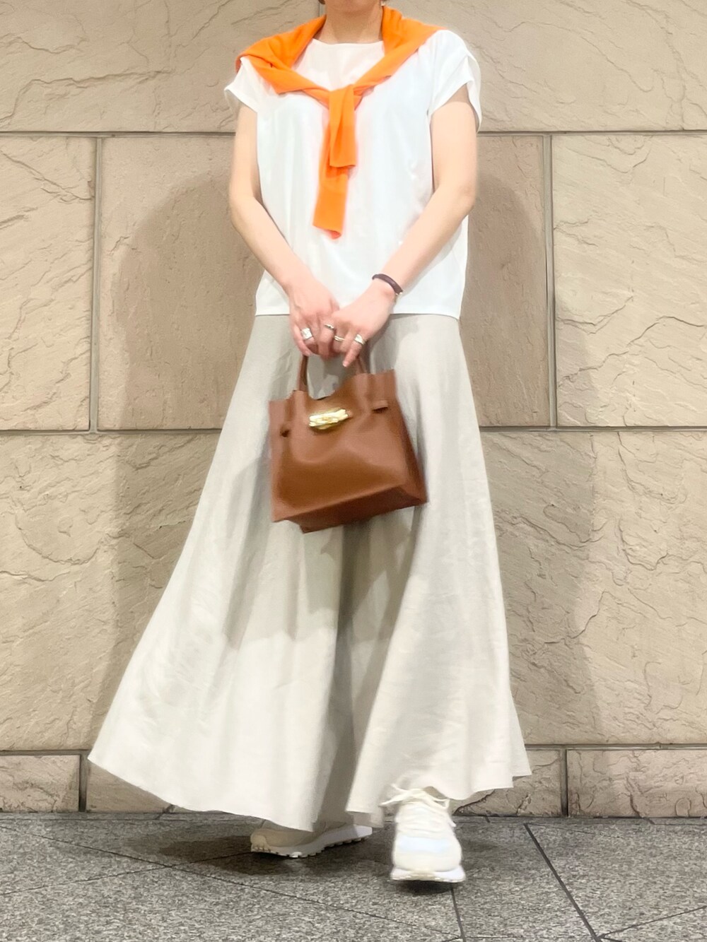 ベージュ系のスカート、ホワイト系のTシャツ/カットソー、ホワイト系のスニーカーを着用したレディースの夏コーディネートの2枚目の写真