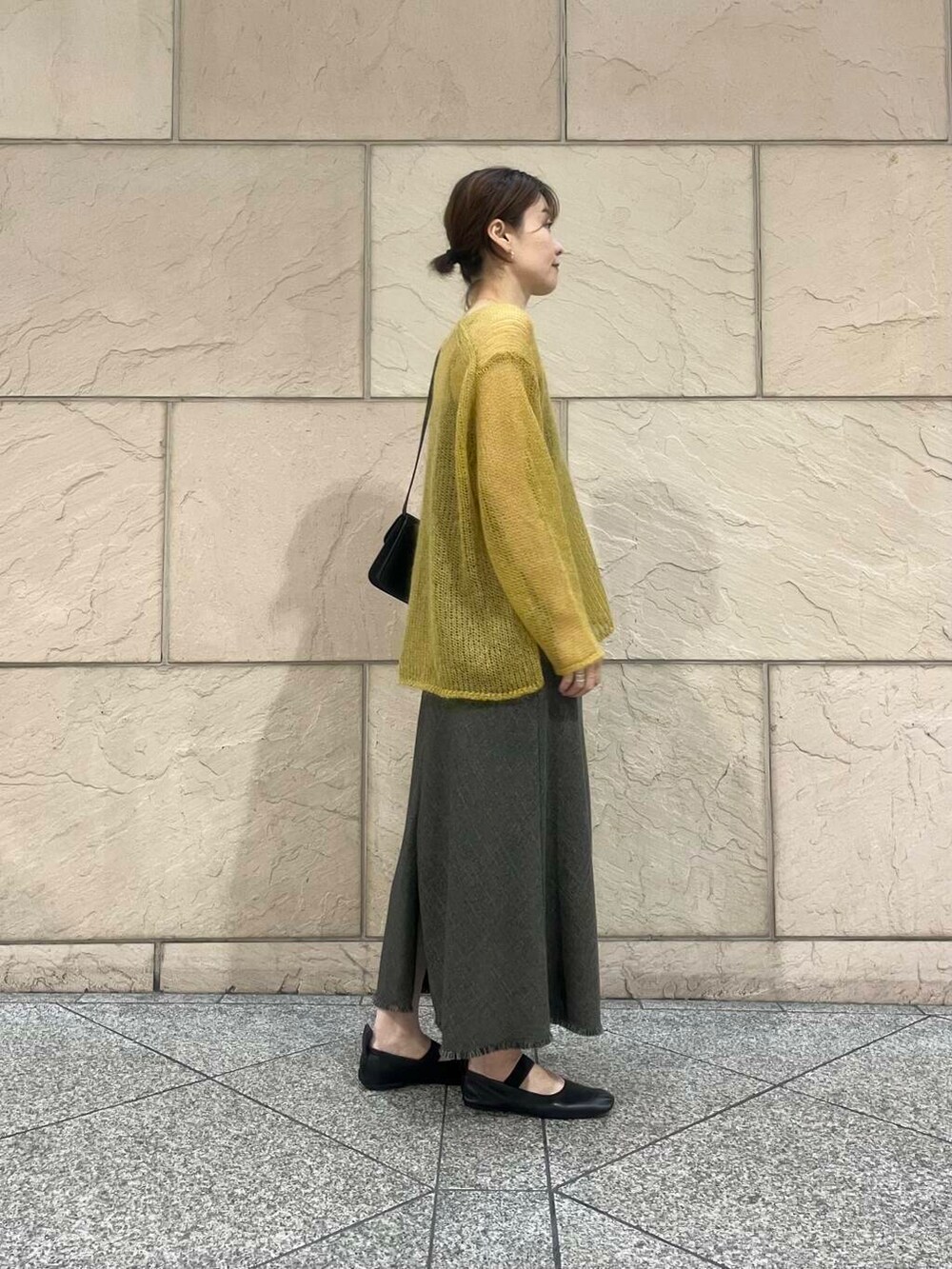 イエロー系のニット/セーター、ブラウン系のワンピース、ブラック系のショルダーバッグを着用したレディースの秋コーディネートの4枚目の写真