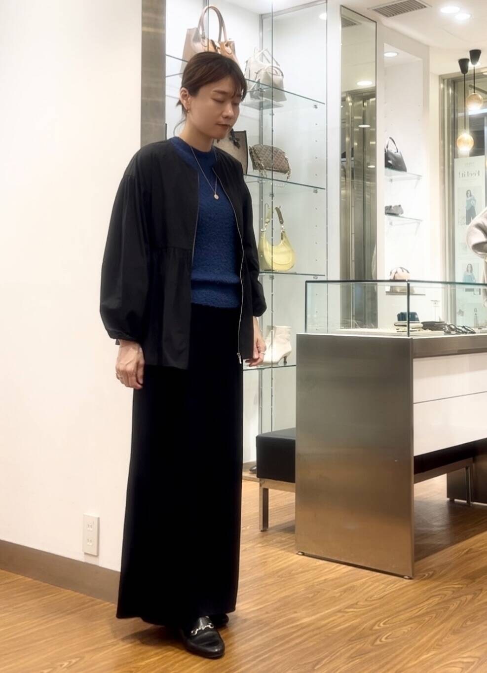 ブラック系のシャツ/ブラウス、ブルー系のニット/セーター、ベージュ系のハンドバッグを着用したレディースの秋コーディネートの4枚目の写真