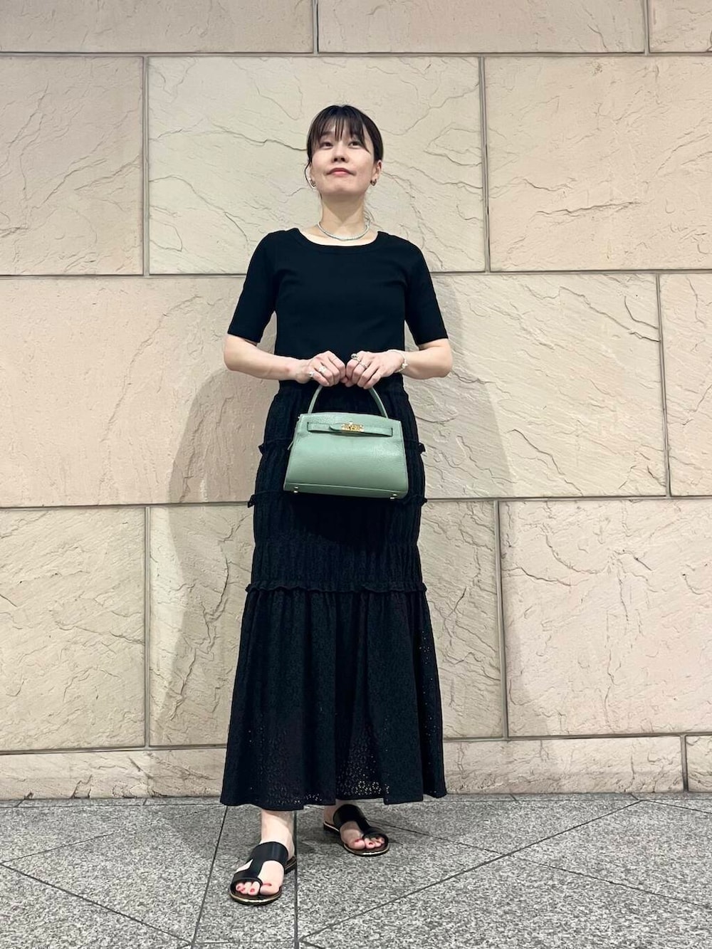 グリーン系のハンドバッグ、ブラック系のTシャツ/カットソーを着用したレディースの夏コーディネートの2枚目の写真