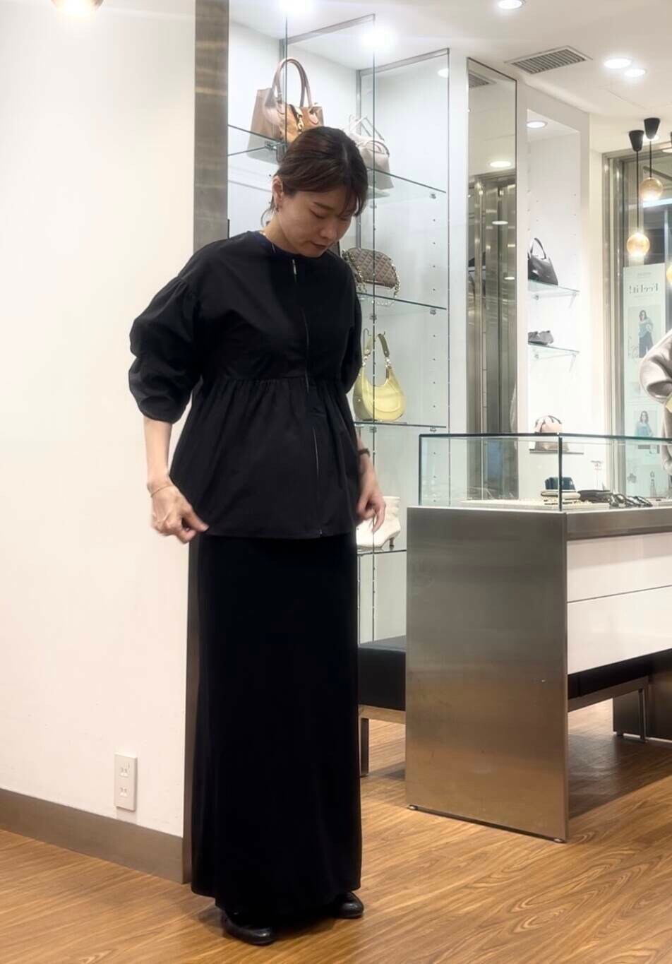 ブラック系のシャツ/ブラウス、ブルー系のニット/セーター、ベージュ系のハンドバッグを着用したレディースの秋コーディネートの2枚目の写真