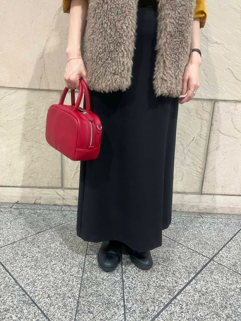 ブラウン系のベスト、オレンジ系のシャツ/ブラウス、ブラック系のスカートを着用したレディースの秋コーディネートの4枚目の写真