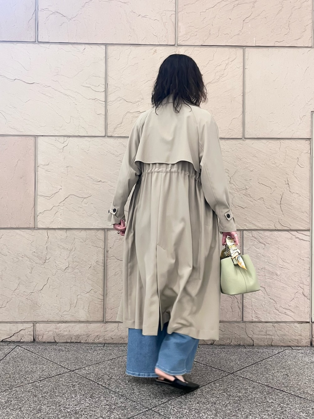 ブルー系のデニムパンツ、ベージュ系のトレンチコート、グリーン系のショルダーバッグを着用したレディースの春コーディネートの3枚目の写真