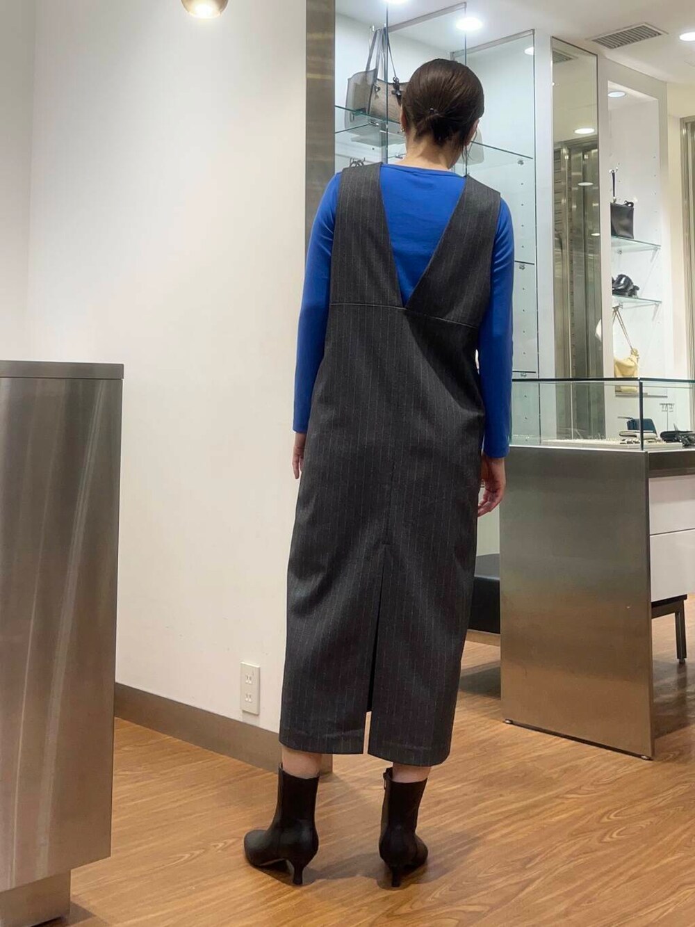 ブラウン系のハンドバッグ、ブルー系のTシャツ/カットソー、ブラック系のブーツを着用したレディースの秋コーディネートの2枚目の写真