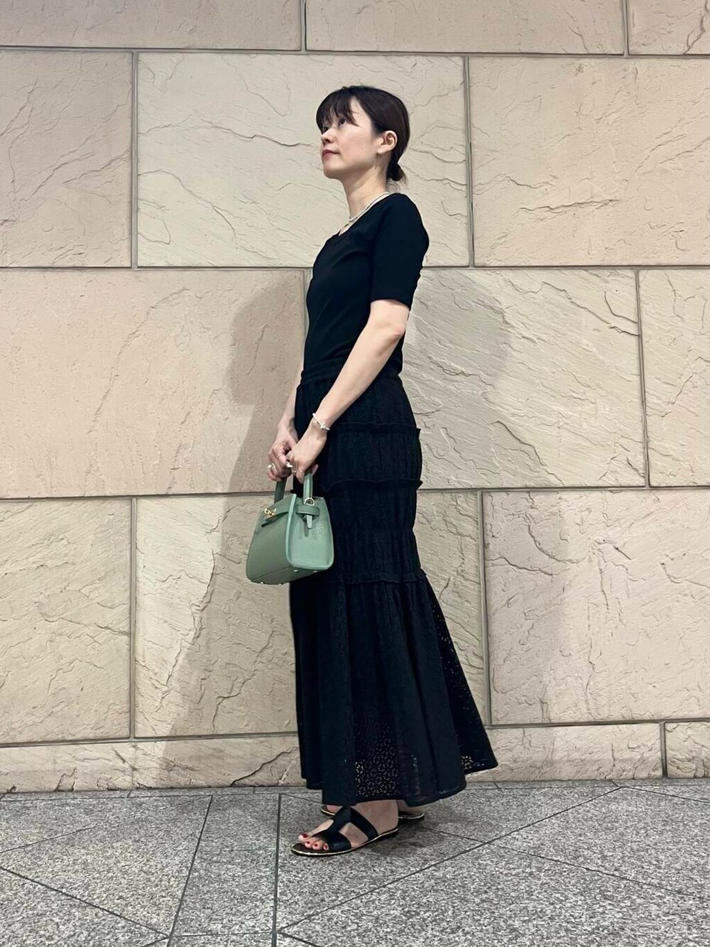 グリーン系のハンドバッグ、ブラック系のTシャツ/カットソーを着用したレディースの夏コーディネートの4枚目の写真