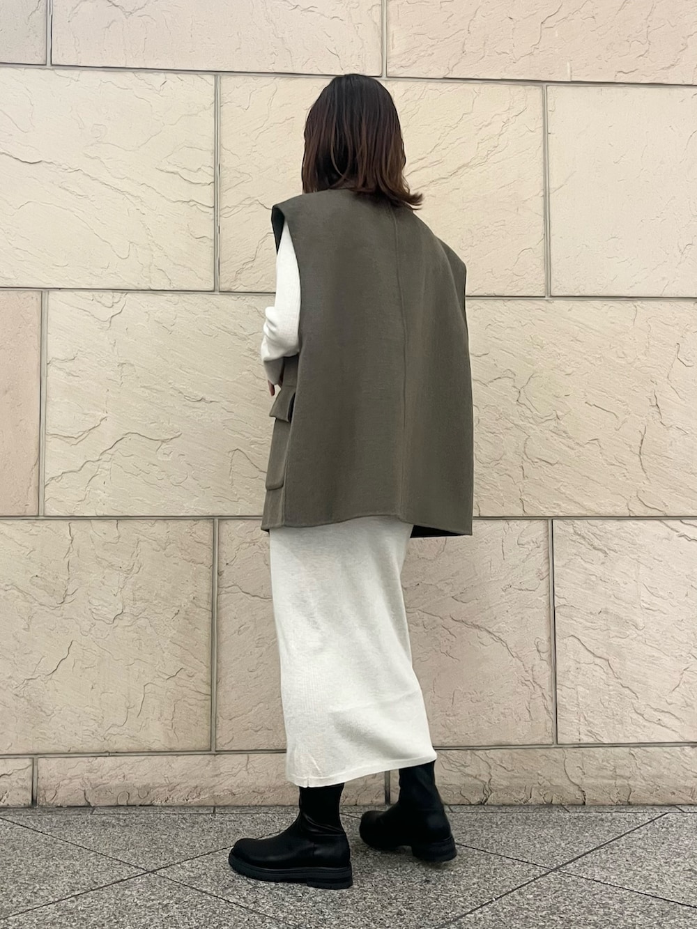 ブラウン系のハンドバッグ、ブラック系のブーツ、グリーン系のその他アウターを着用したレディースの秋コーディネートの3枚目の写真