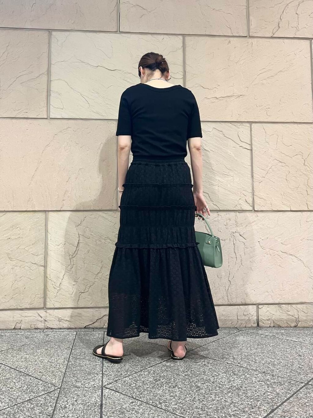 グリーン系のハンドバッグ、ブラック系のTシャツ/カットソーを着用したレディースの夏コーディネートの3枚目の写真