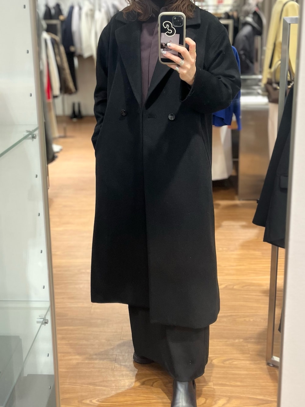 ブラック系のチェスターコート、レッド系のシャツ/ブラウス、ゴールド系のピアス（両耳用）を着用したレディースの冬コーディネートの3枚目の写真