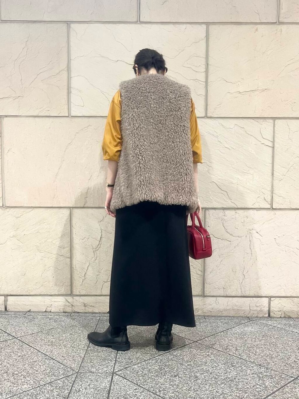 ブラウン系のベスト、オレンジ系のシャツ/ブラウス、ブラック系のスカートを着用したレディースの秋コーディネートの2枚目の写真