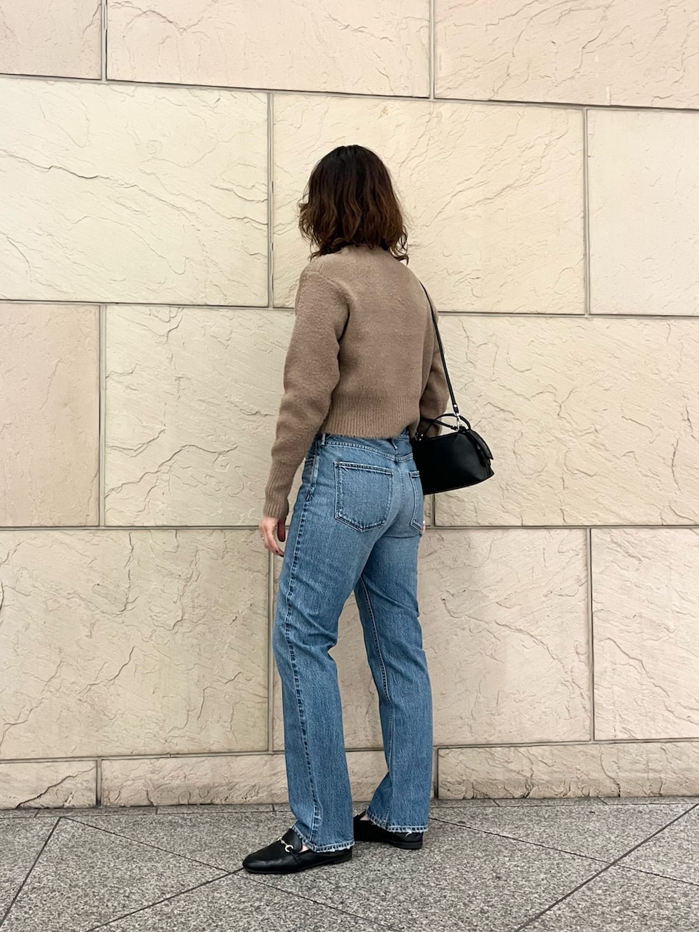 イエロー系のカーディガン/ボレロ、ブルー系のデニムパンツ、ブラック系のハンドバッグを着用したレディースの秋コーディネートの5枚目の写真