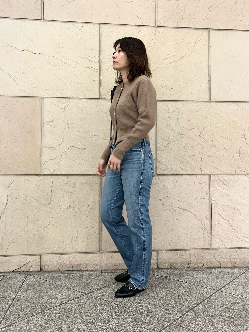 イエロー系のカーディガン/ボレロ、ブルー系のデニムパンツ、ブラック系のハンドバッグを着用したレディースの秋コーディネートの3枚目の写真