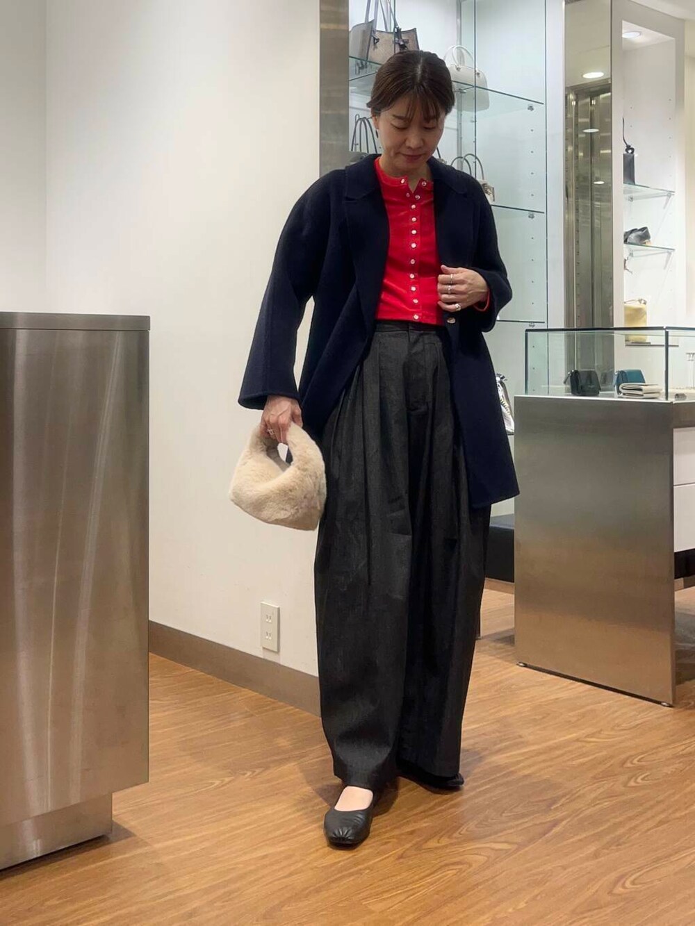 レッド系のカーディガン/ボレロ、ブルー系のチェスターコート、ブラック系のデニムパンツを着用したレディースの秋コーディネートの4枚目の写真