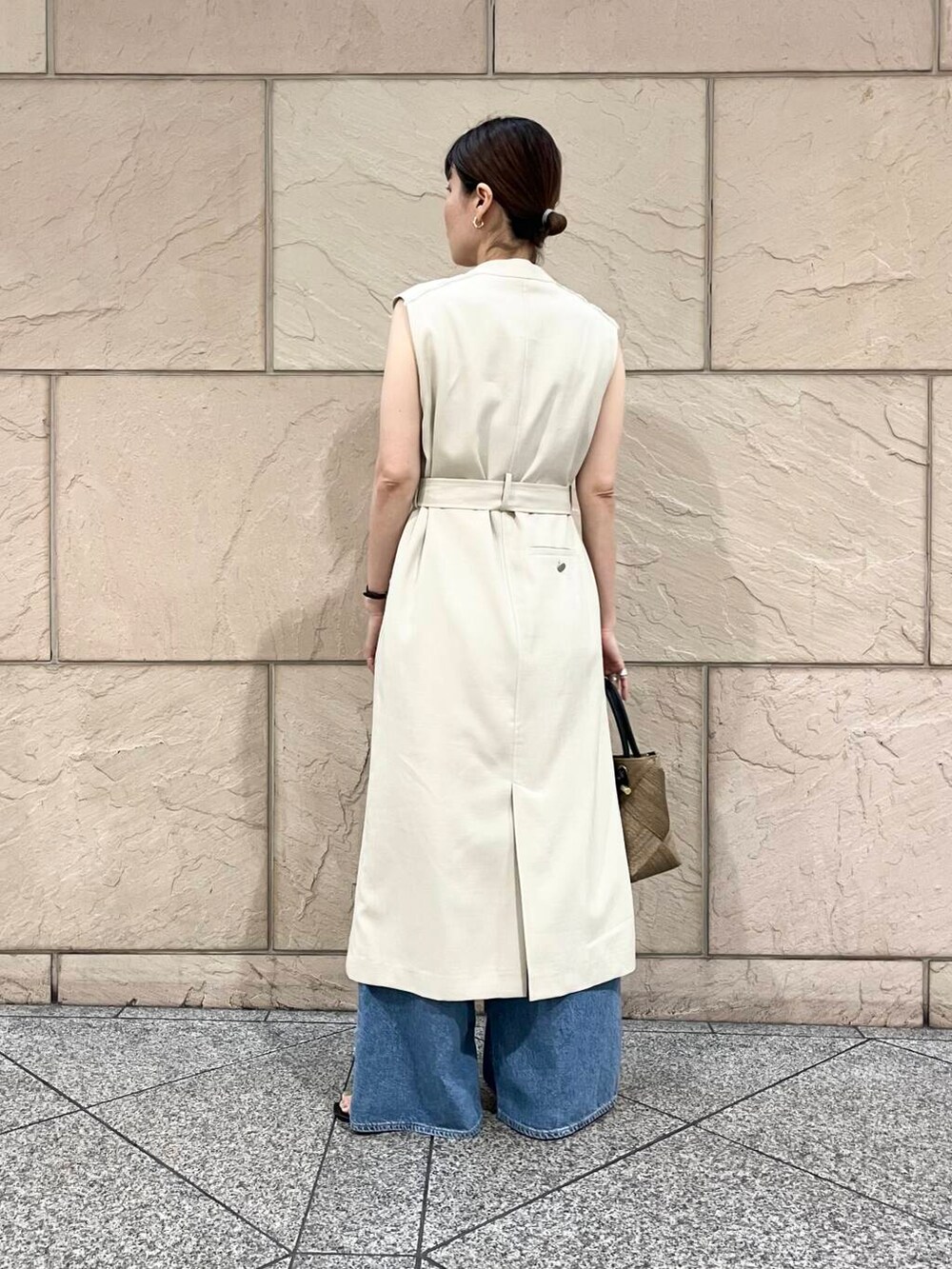 ベージュ系のワンピース、ブルー系のデニムパンツ、ベージュ系のネックレスを着用したレディースの春コーディネートの2枚目の写真