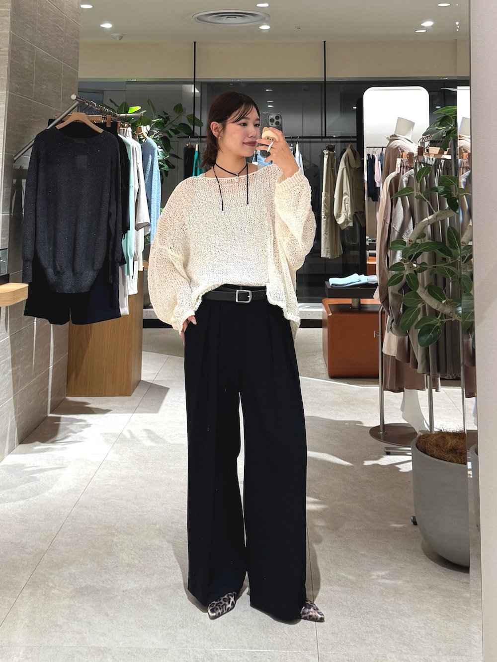 ホワイト系のニット/セーター、ブラック系のスラックス、ブラック系のベルトを着用したレディースの春コーディネートの2枚目の写真