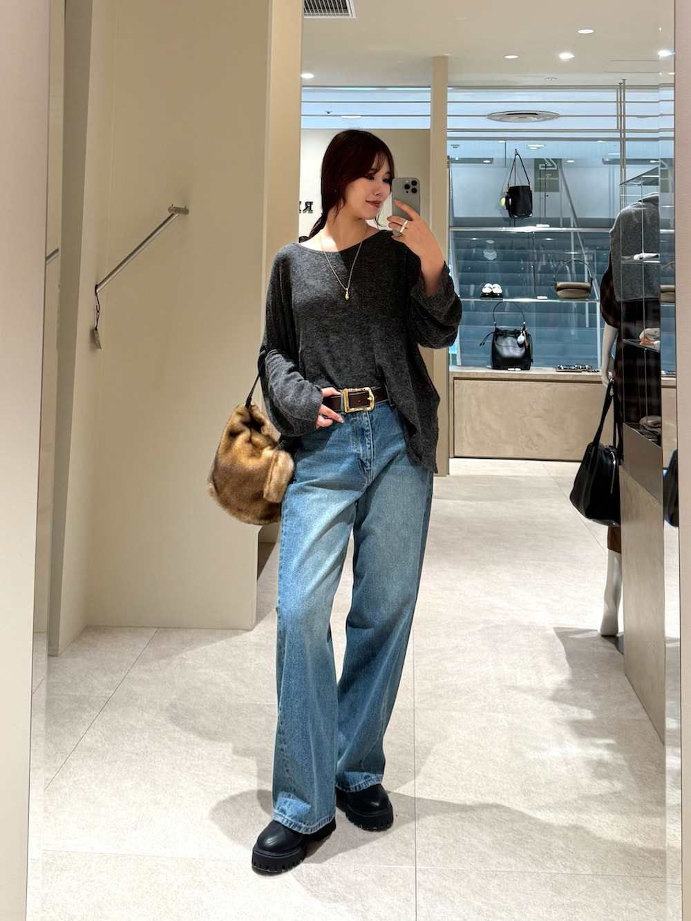 ブルー系のデニムパンツ、グレー系のニット/セーター、イエロー系のハンドバッグを着用したレディースの秋コーディネートの2枚目の写真