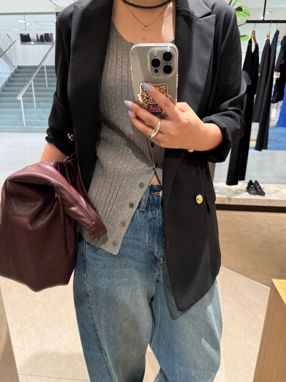 ブラック系のテーラードジャケット、ブルー系のデニムパンツ、ブラウン系のショルダーバッグを着用したレディースの夏コーディネートの3枚目の写真