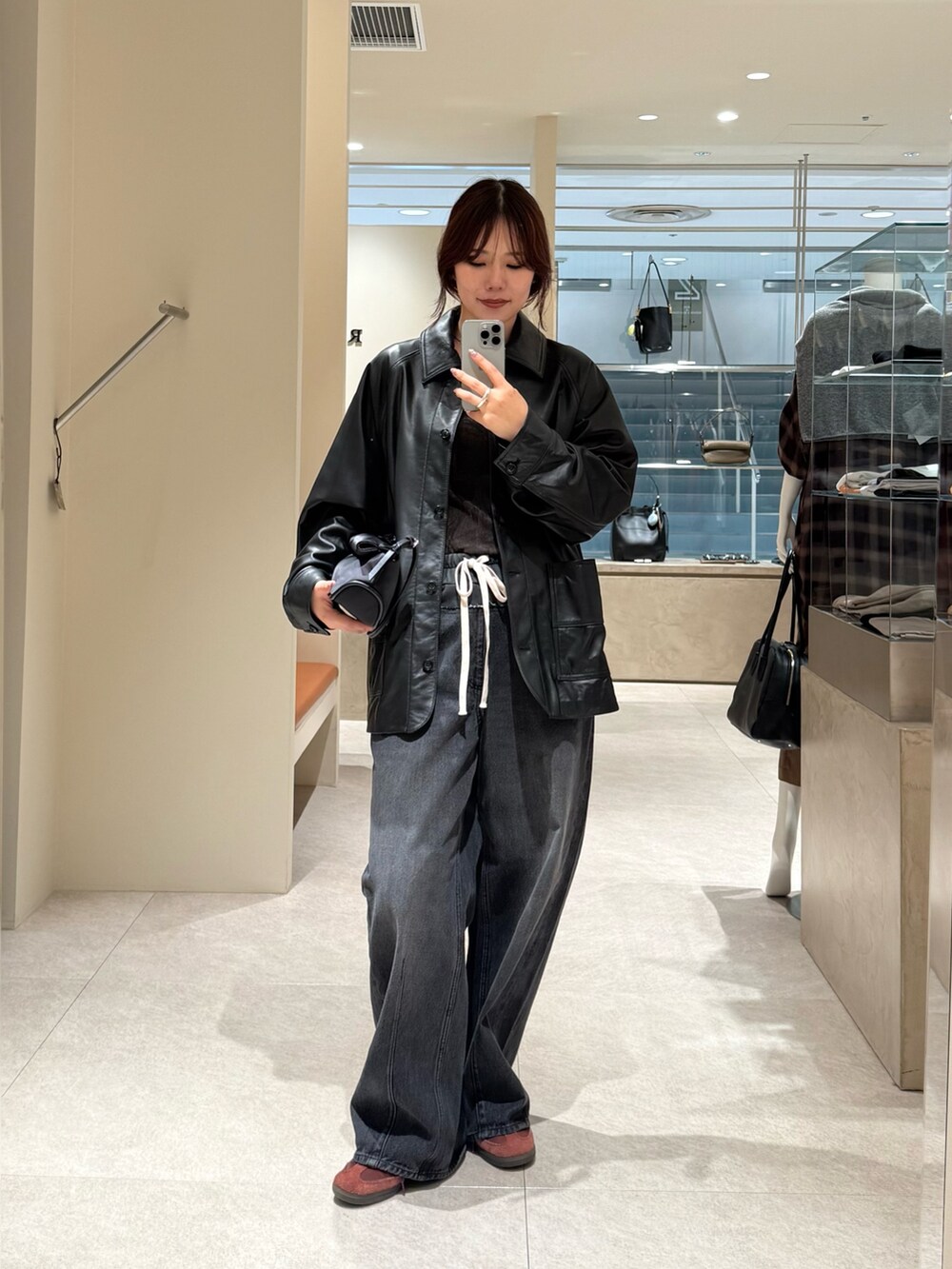 ブラック系のデニムパンツ、ブラック系のその他アウターを着用したレディースの秋コーディネートの2枚目の写真