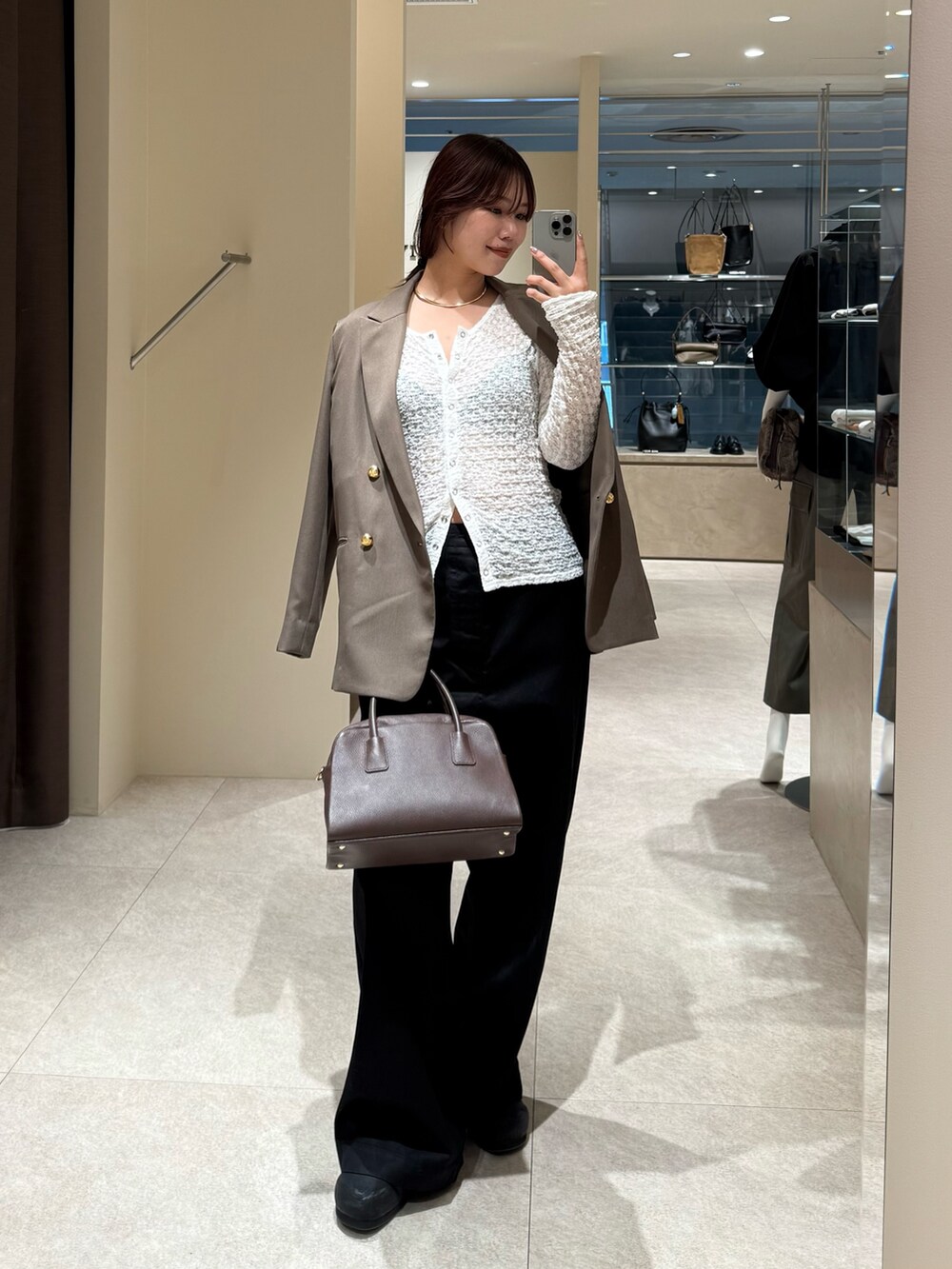 ブラック系のチノパンツ、ブラウン系のテーラードジャケット、ブラウン系のボストンバッグを着用したレディースの秋コーディネートの2枚目の写真