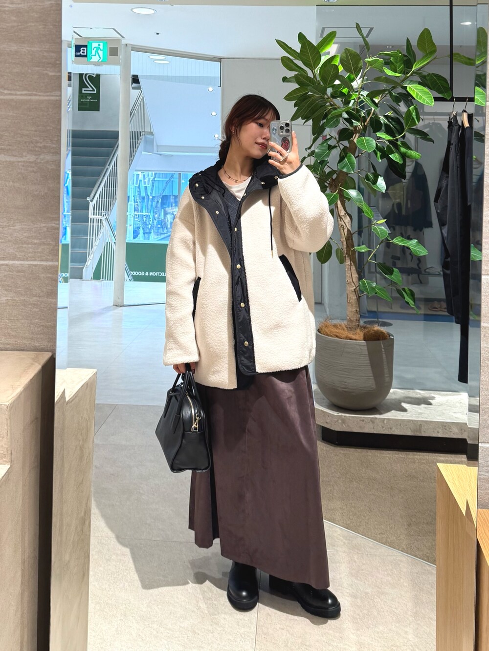 ホワイト系のその他アウター、ブラック系のボストンバッグ、ブラウン系のスカートを着用したレディースの秋コーディネートの2枚目の写真