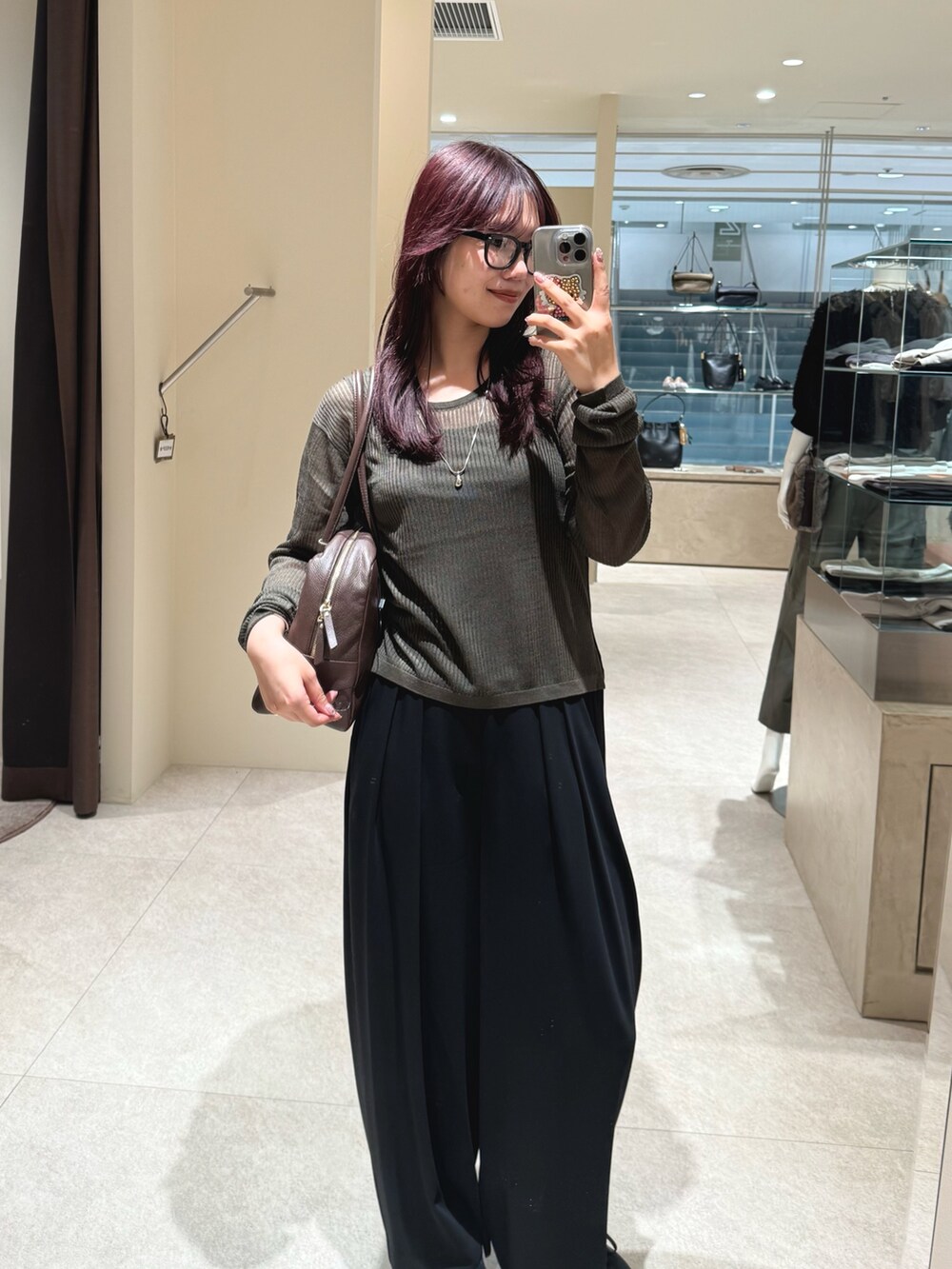 グリーン系のニット/セーター、ブラック系のスラックス、ブラウン系のボストンバッグを着用したレディースの秋コーディネートの4枚目の写真