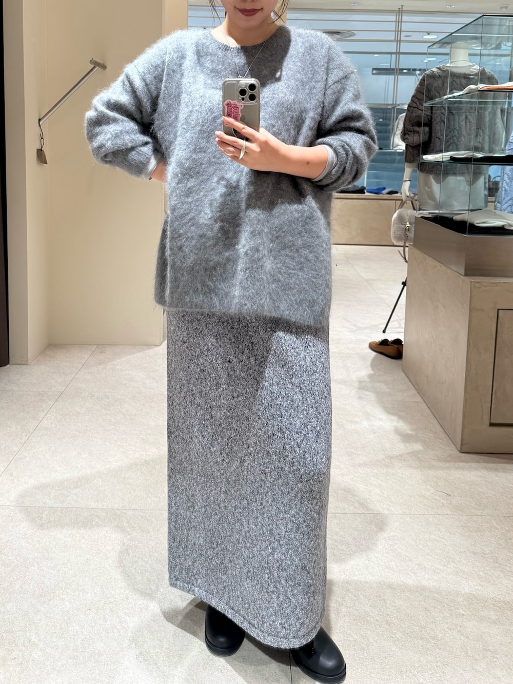 グレー系のニット/セーター、グレー系のスカート、ブラック系のブーツを着用したレディースの秋コーディネートの5枚目の写真