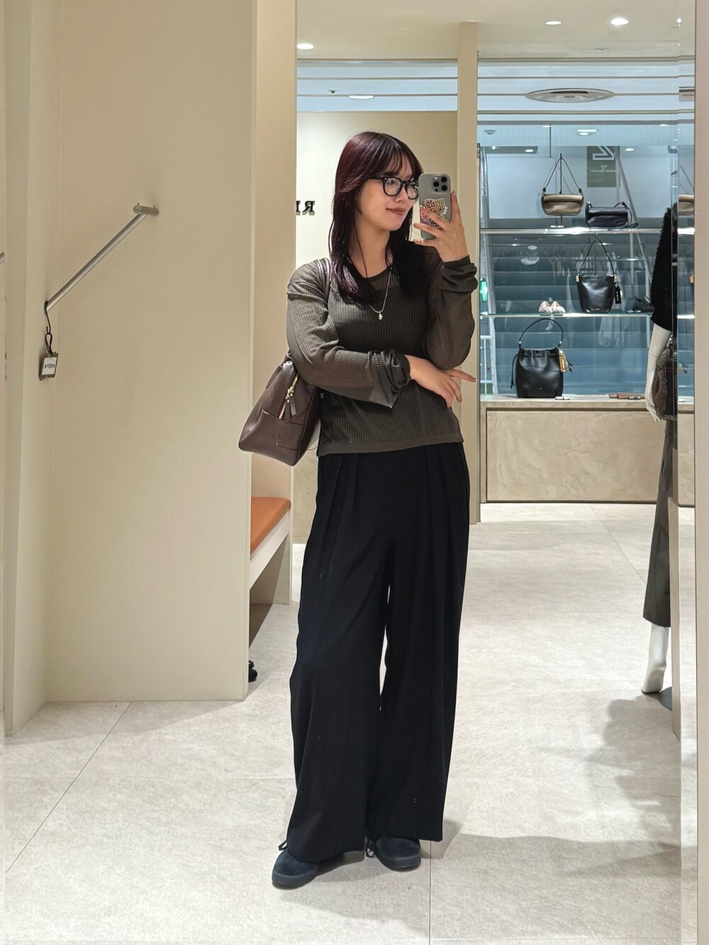 グリーン系のニット/セーター、ブラック系のスラックス、ブラウン系のボストンバッグを着用したレディースの秋コーディネートの2枚目の写真