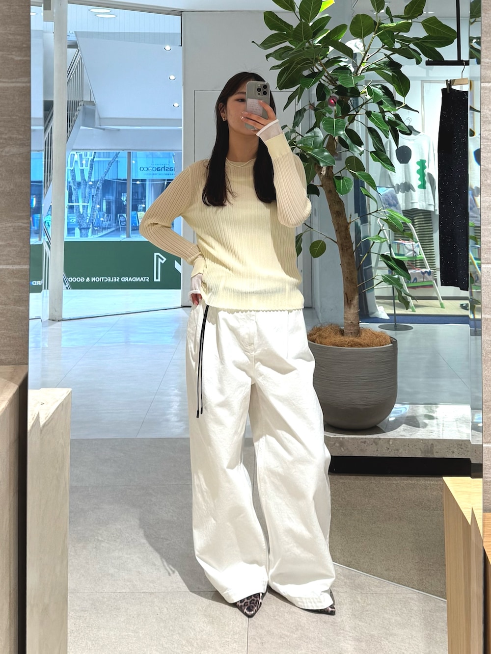 イエロー系のニット/セーター、ホワイト系のデニムパンツ、ブラック系のベルトを着用したレディースの冬コーディネートの2枚目の写真