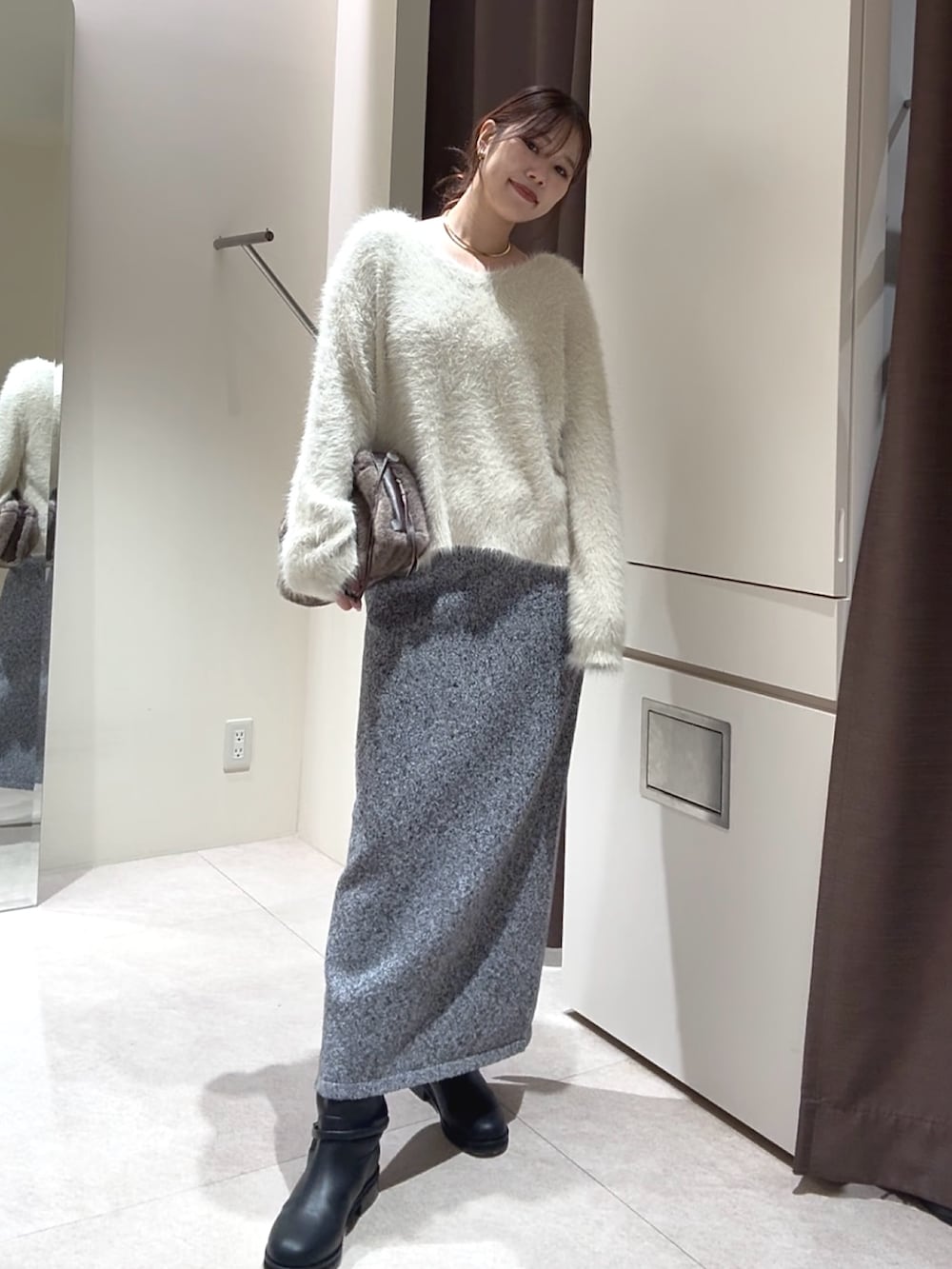 ホワイト系のニット/セーター、グレー系のスカート、ブラック系のブーツを着用したレディースの秋コーディネートの2枚目の写真