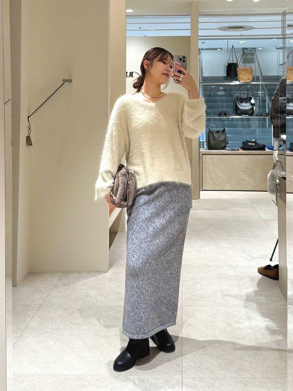 ホワイト系のニット/セーター、グレー系のスカート、ブラック系のブーツを着用したレディースの秋コーディネートの4枚目の写真