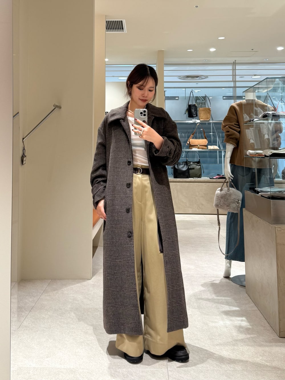 ベージュ系のチノパンツ、ブラウン系のステンカラーコート、ホワイト系のTシャツ/カットソーを着用したレディースの秋コーディネートの2枚目の写真