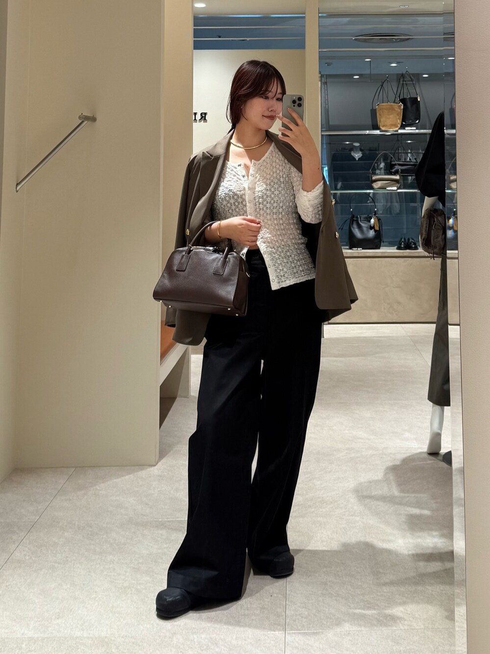 ブラック系のチノパンツ、ブラウン系のテーラードジャケット、ブラウン系のボストンバッグを着用したレディースの秋コーディネートの5枚目の写真