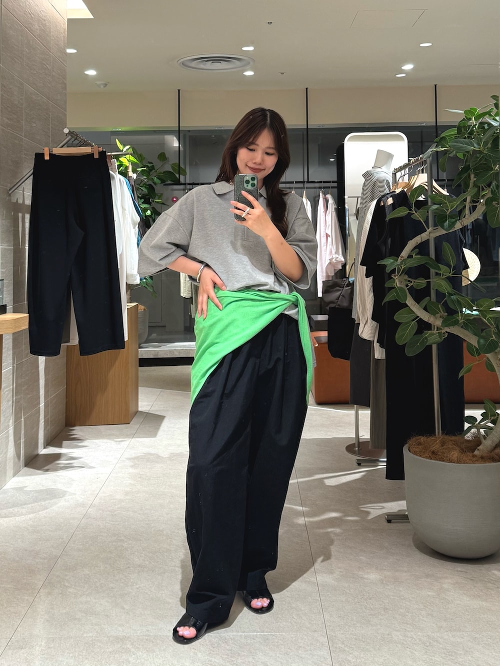 グレー系のポロシャツ、ブラック系のその他パンツ、グリーン系のストール/ショールを着用したレディースの春コーディネートの3枚目の写真