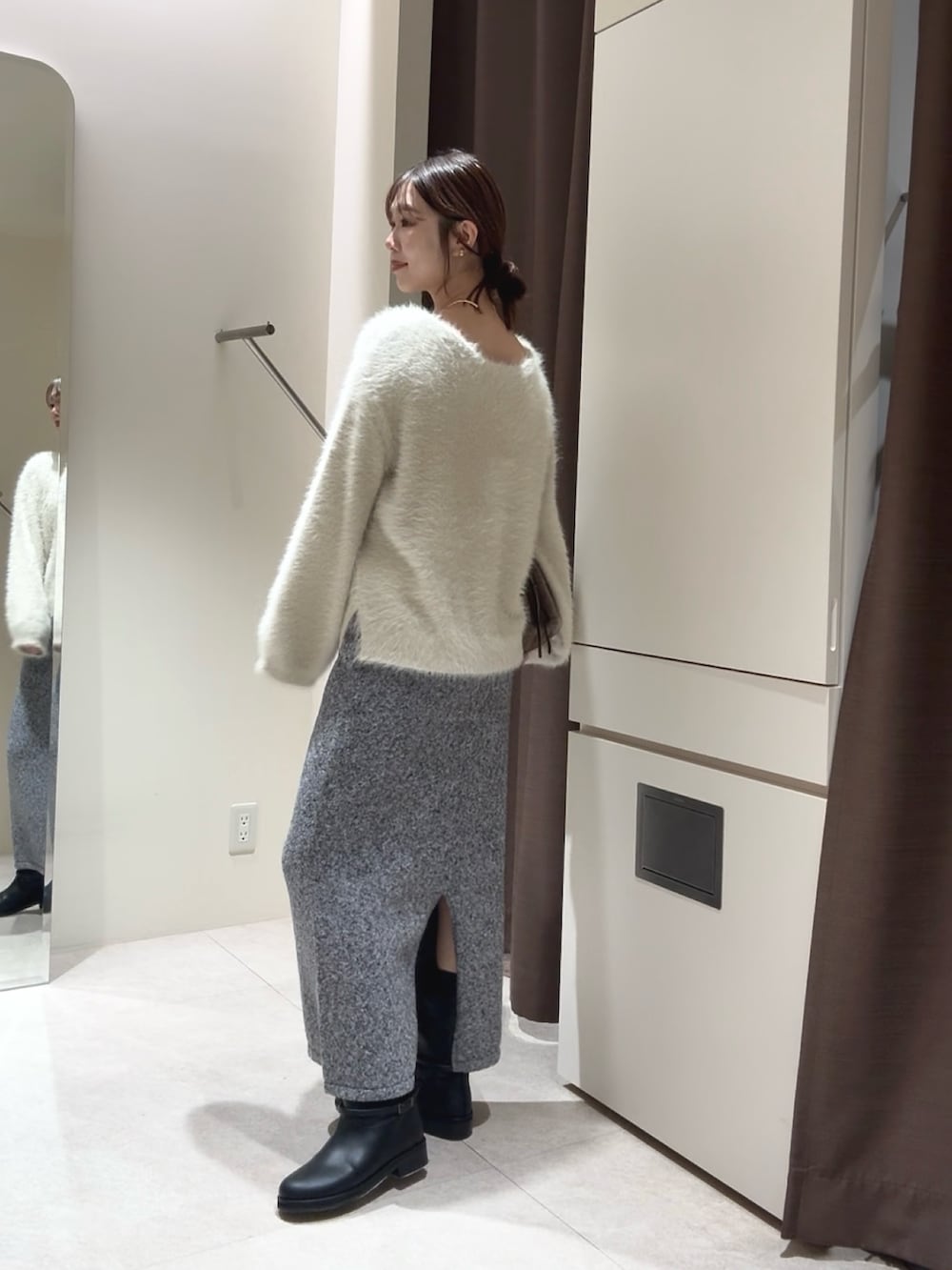 ホワイト系のニット/セーター、グレー系のスカート、ブラック系のブーツを着用したレディースの秋コーディネートの3枚目の写真