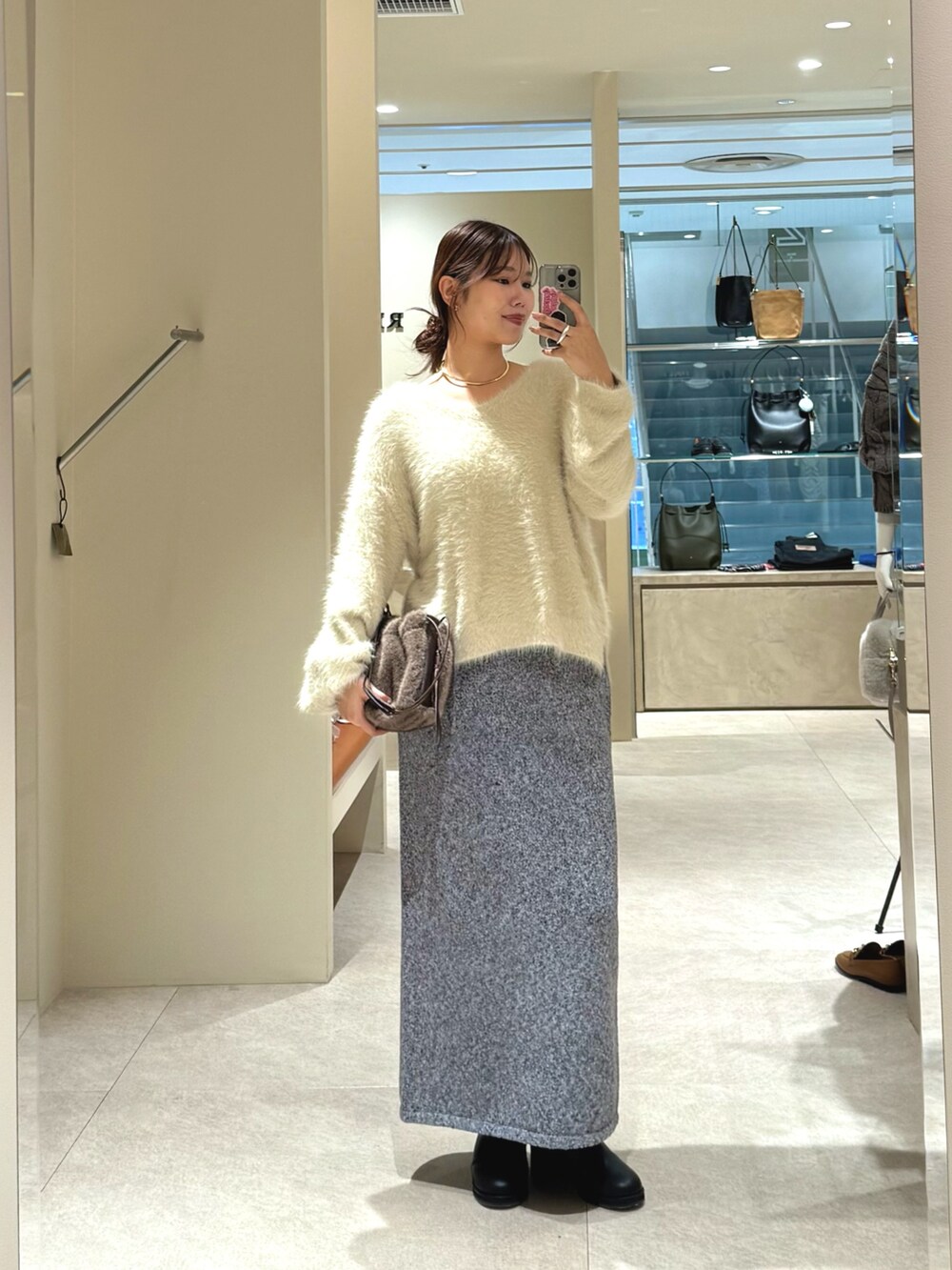 ホワイト系のニット/セーター、グレー系のスカート、ブラック系のブーツを着用したレディースの秋コーディネートの5枚目の写真