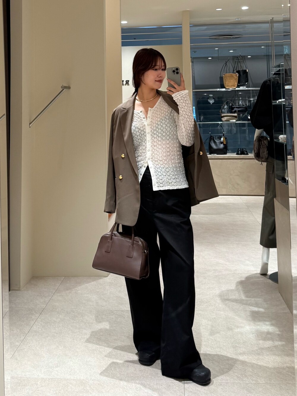 ブラック系のチノパンツ、ブラウン系のテーラードジャケット、ブラウン系のボストンバッグを着用したレディースの秋コーディネートの3枚目の写真