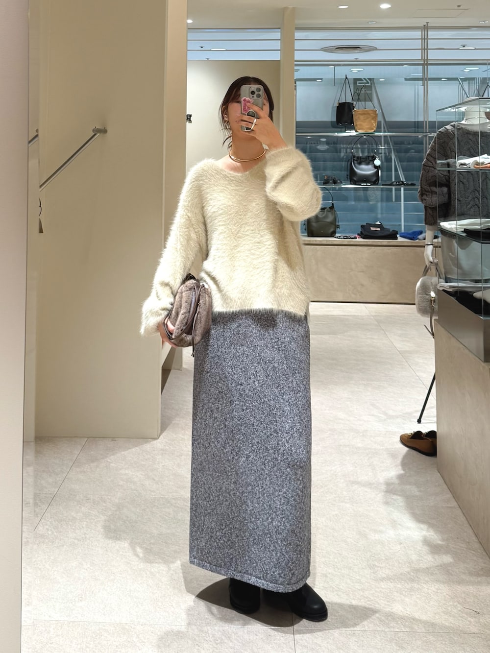 ホワイト系のニット/セーター、グレー系のスカート、ブラック系のブーツを着用したレディースの秋コーディネートの6枚目の写真