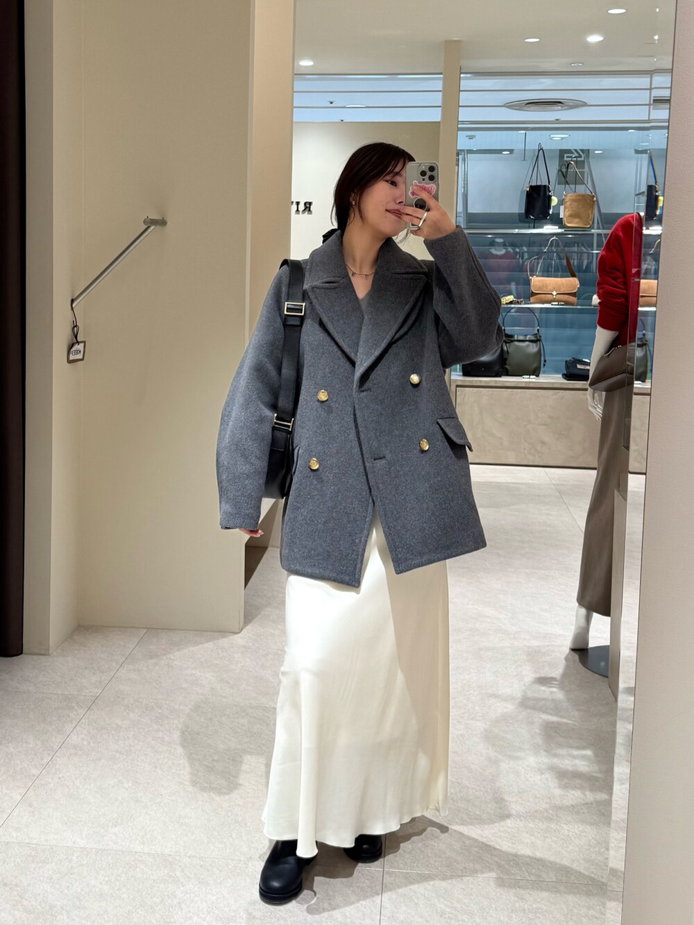 グレー系のピーコート、ホワイト系のスカートを着用したレディースの秋コーディネートの2枚目の写真