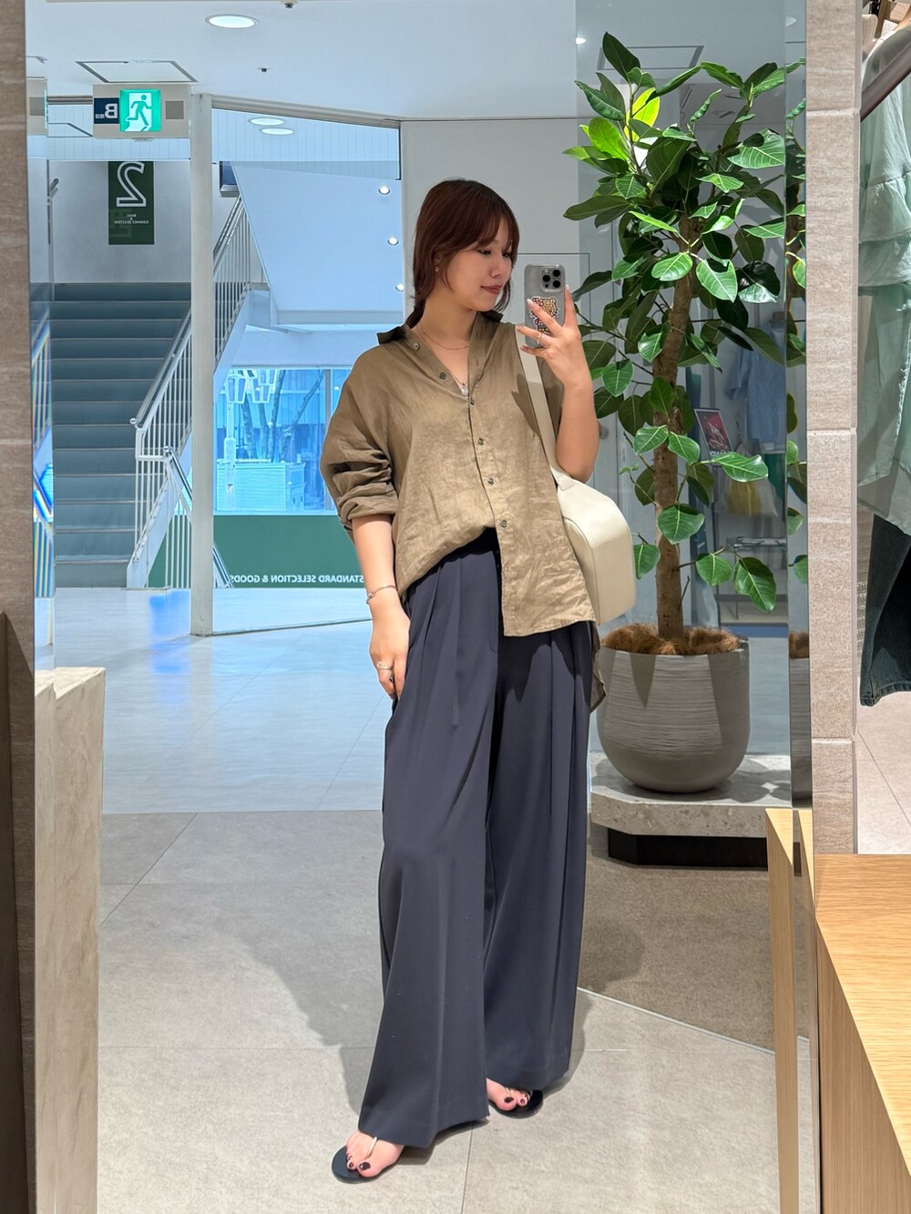 グレー系のスラックス、ブラウン系のシャツ/ブラウス、ホワイト系のハンドバッグを着用したレディースの夏コーディネートの3枚目の写真