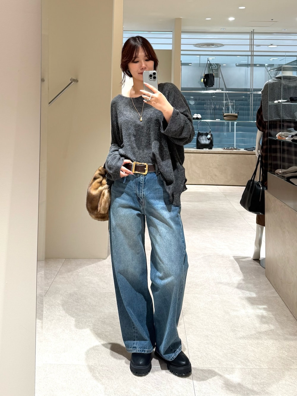 ブルー系のデニムパンツ、グレー系のニット/セーター、イエロー系のハンドバッグを着用したレディースの秋コーディネートの4枚目の写真