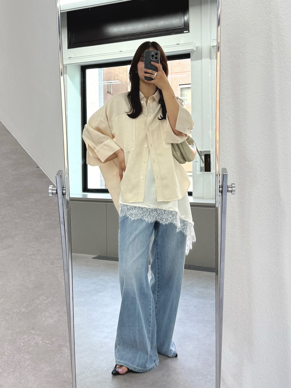 ブルー系のデニムパンツ、ホワイト系のキャミソール、ゴールド系のショルダーバッグを着用したレディースの春コーディネートの2枚目の写真