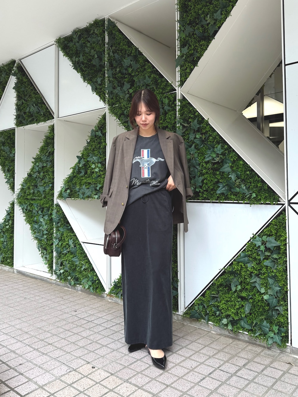 ブラウン系のテーラードジャケット、グレー系のTシャツ/カットソー、ブラック系のスカートを着用したレディースの夏コーディネートの3枚目の写真