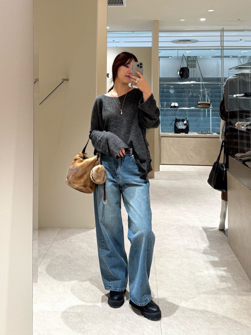 ブルー系のデニムパンツ、グレー系のニット/セーター、イエロー系のハンドバッグを着用したレディースの秋コーディネートの5枚目の写真