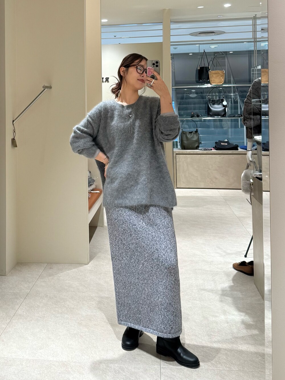 グレー系のニット/セーター、グレー系のスカート、ブラック系のブーツを着用したレディースの秋コーディネートの3枚目の写真