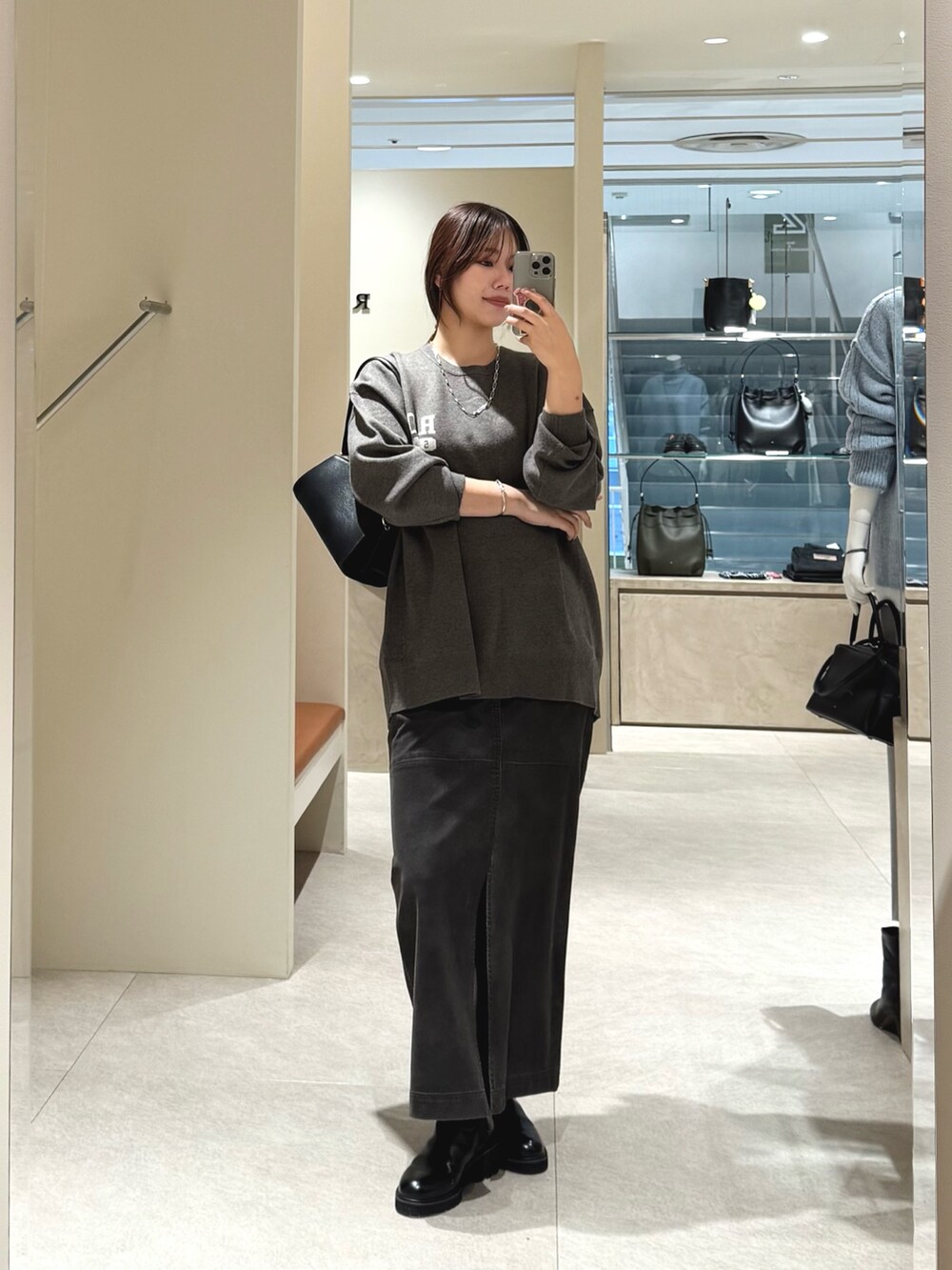 グレー系のニット/セーター、グレー系のスカートを着用したレディースの秋コーディネートの2枚目の写真