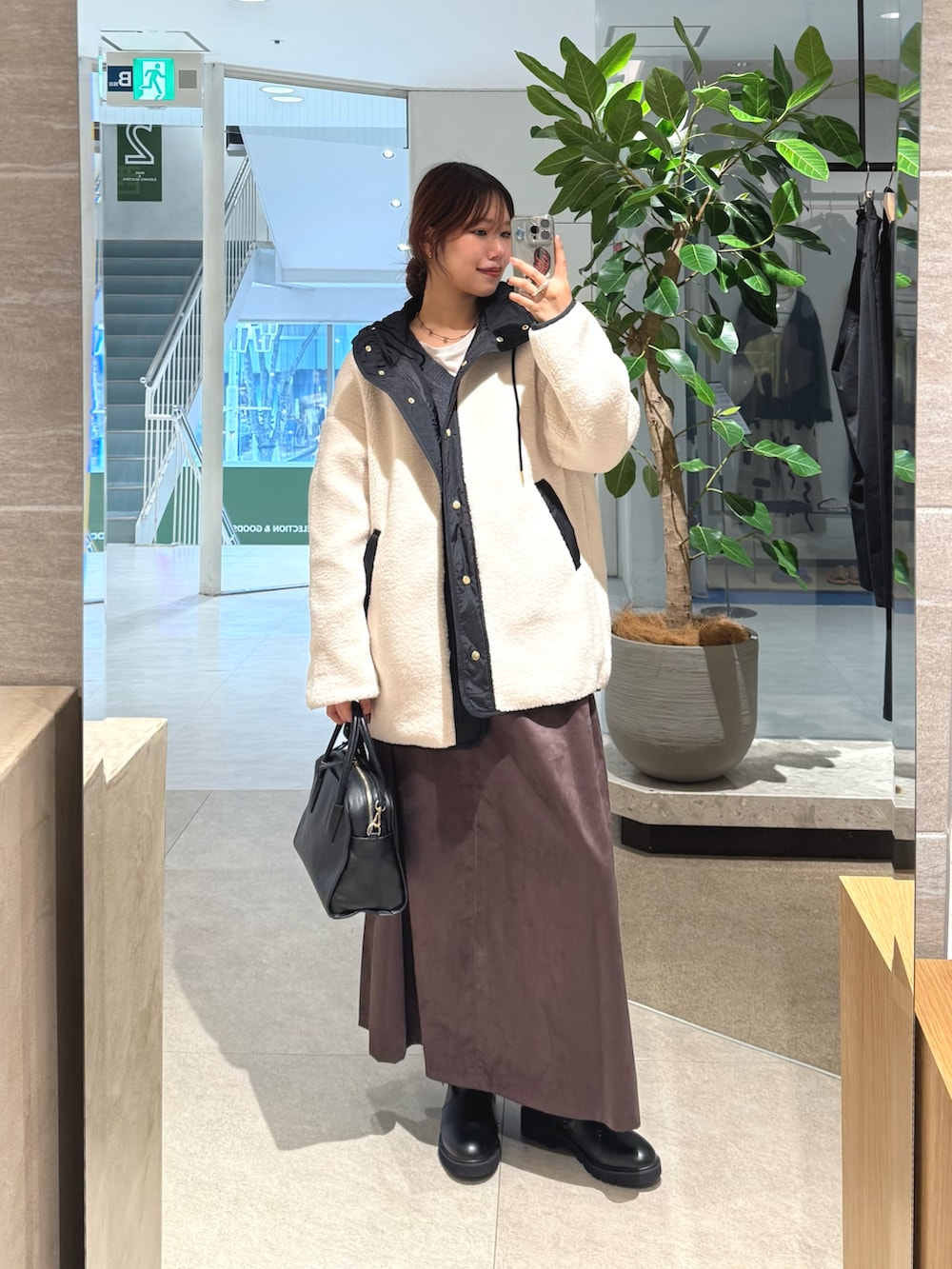 ホワイト系のその他アウター、ブラック系のボストンバッグ、ブラウン系のスカートを着用したレディースの秋コーディネートの3枚目の写真