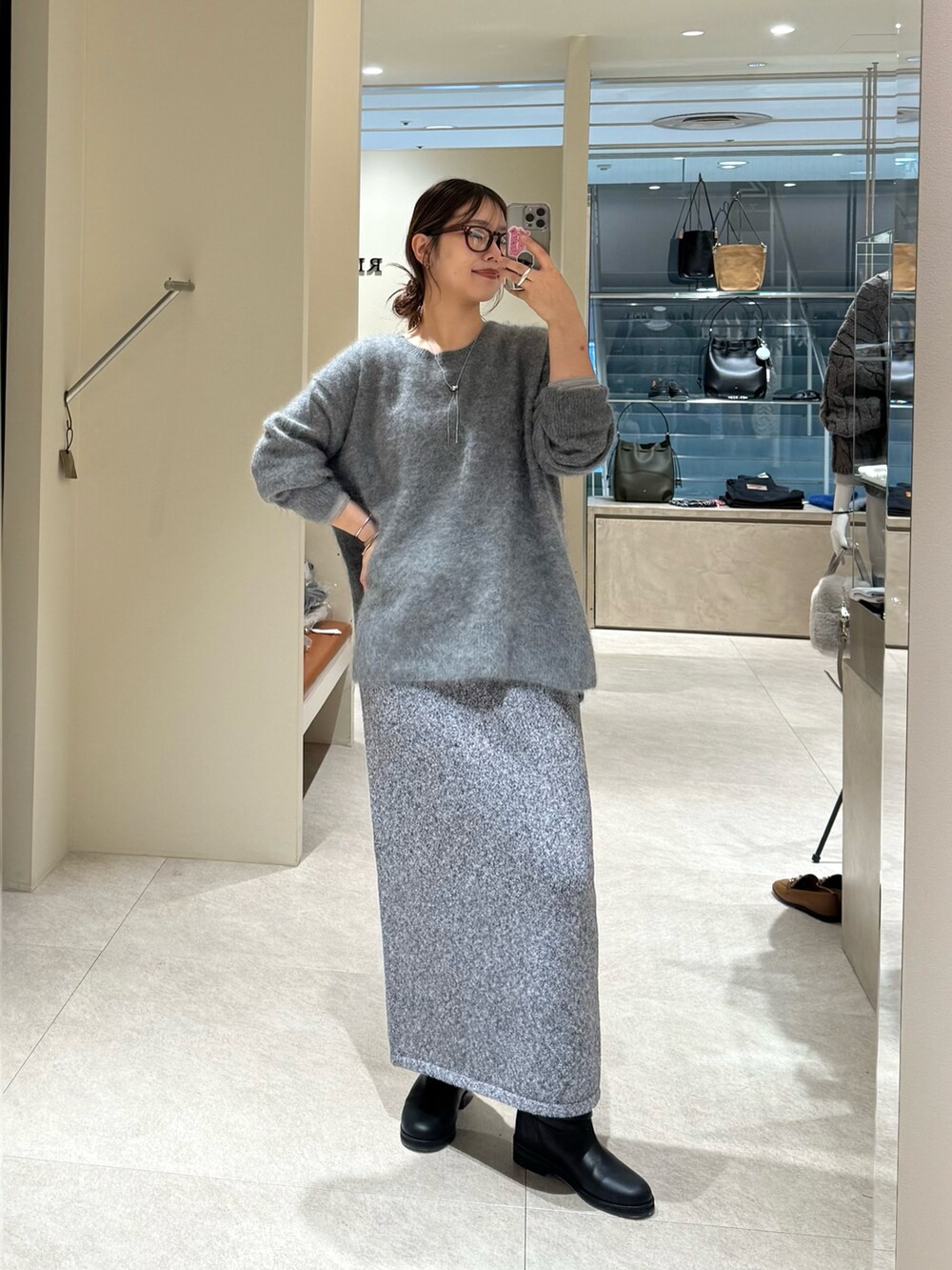グレー系のニット/セーター、グレー系のスカート、ブラック系のブーツを着用したレディースの秋コーディネートの4枚目の写真