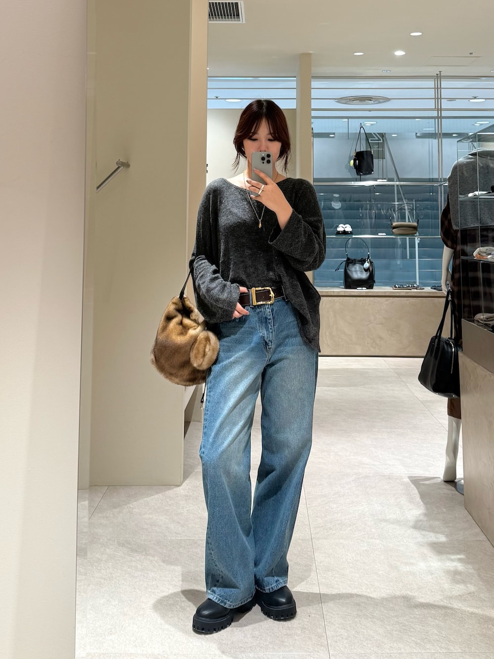 ブルー系のデニムパンツ、グレー系のニット/セーター、イエロー系のハンドバッグを着用したレディースの秋コーディネートの3枚目の写真