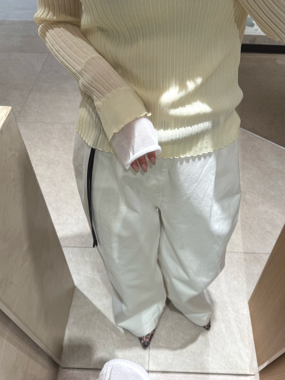 イエロー系のニット/セーター、ホワイト系のデニムパンツ、ブラック系のベルトを着用したレディースの冬コーディネートの3枚目の写真